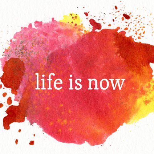 a splat of red/yellow/orange watercolour paint with the words 'life is now' in white