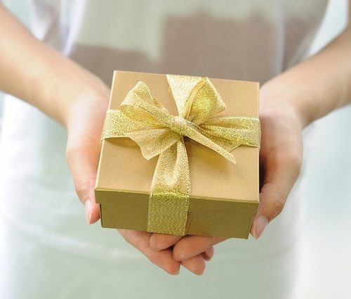 Gold box with gold ribbon in hands